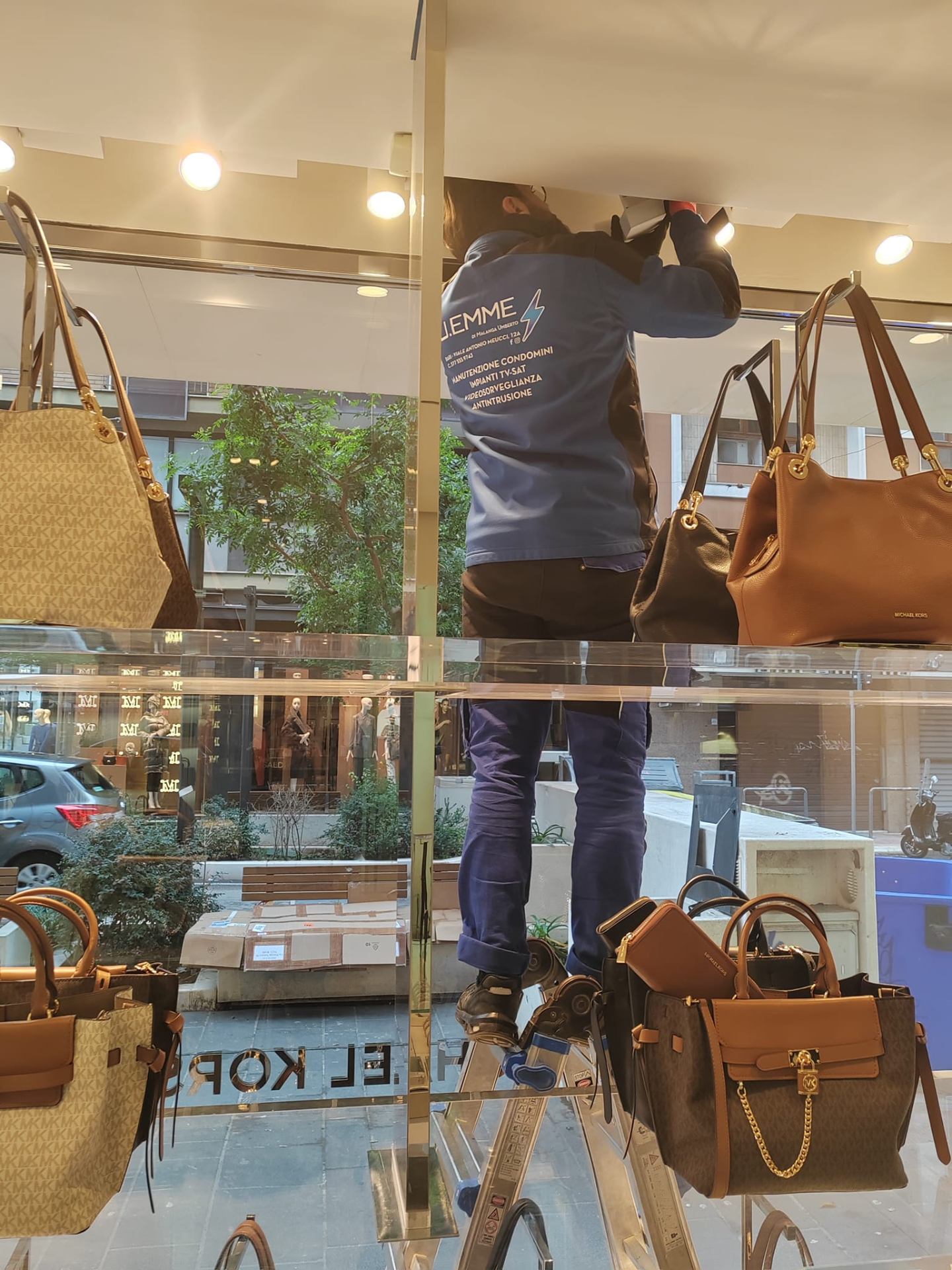Tecnico u.emme al lavoro nella vetrina dello store Michael Kors di Bari
